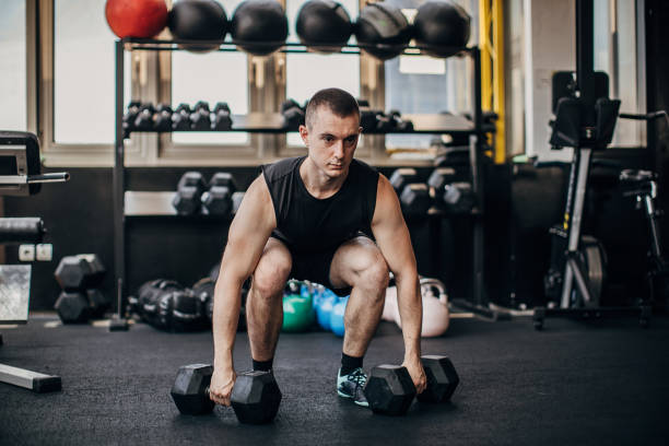 istock Man exercising with dumbbells in gym 1254826365