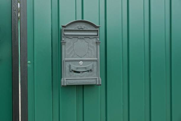 istock iron mailbox hanging on a green metal fence wall 1254827089