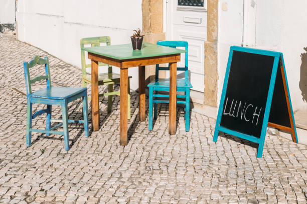 Empty wooden tables outside on a sunny day with a chalkboard sign on side - captured in Cascais, Portugal