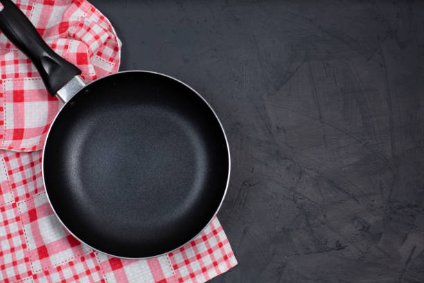 istock Empty black frying pan with kitchen towel on black table. 1254829627