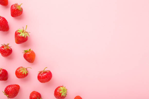 Red bright strawberries on light pink table background. Beautiful fresh berries. Pastel color. Flat lay. Empty place for text. Top down view.