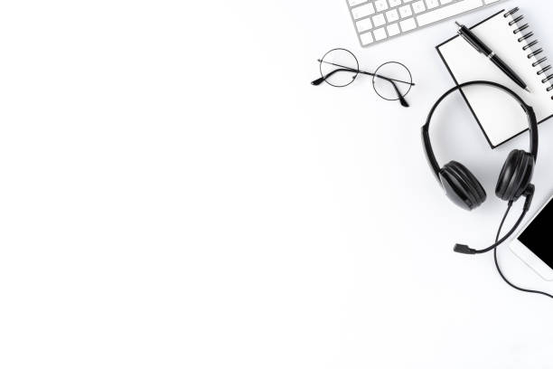 istock Call center desktop with headset and accessories on white table. Top view 1254833106