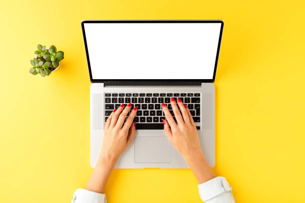 istock Modern workplace with woman’s hand working on laptop with empty screen. Office desktop concept. Top view 1254833248