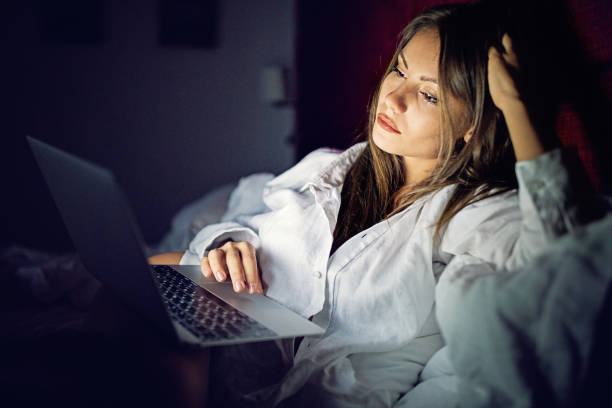 istock Woman is browsing in bed using her laptop 1254833933