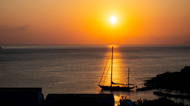 istock Sun setting behind a sailboat docked in a bay 1254834235