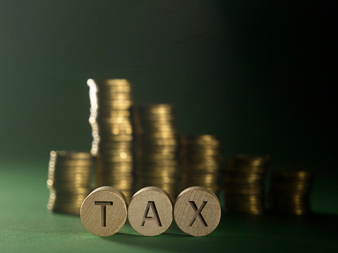 stack of coins and word tax on the green background