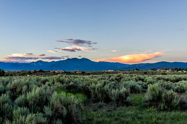 panoramic view of sunset and desert sage brush plants in ranchos de taos valley and green landscape in summer with sunlight on clouds - ranchos de taos imagens e fotografias de stock