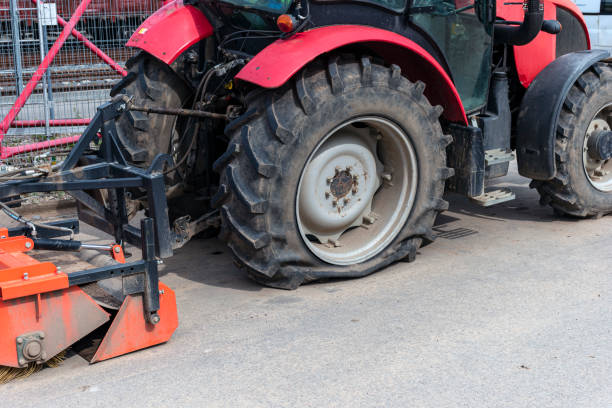 повреждена грязная плоская шина тяжелого трактора на дороге. - tractor repair стоковые фото и изображения