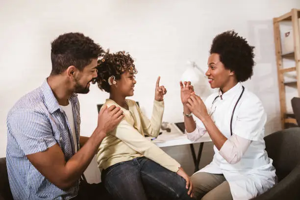 Photo of Smiling deaf girl learning sign language at doctor's office