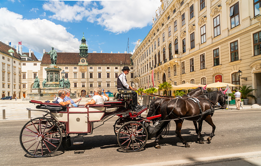 Vienna, Austria - june 24th 2020 - Tourists getting a horse carriage ride through the Hofburg Castle, the house of Sisi, during Corona time on a sunny day