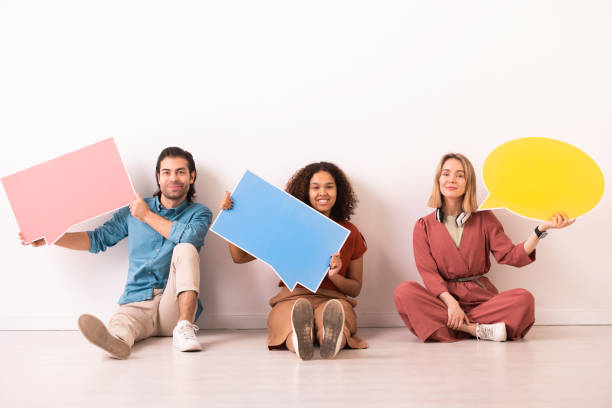 istock Three happy young intercultural millennials showing large paper speech bubbles 1254848418