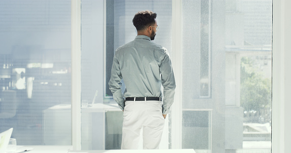 Shot of a young businessman looking out his office window