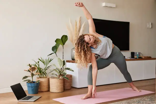 Shot of a young woman practicing her yoga routine at home