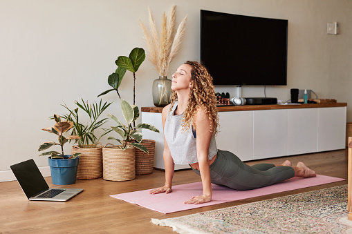 Shot of a young woman practicing her yoga routine at home