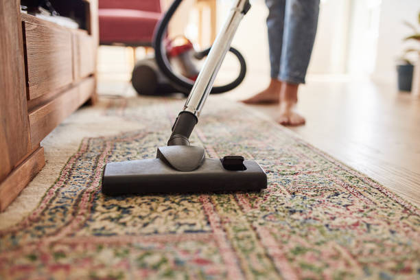 Dust mites don't stand a chance Shot of a young woman vacuuming the living room at home rug stock pictures, royalty-free photos & images
