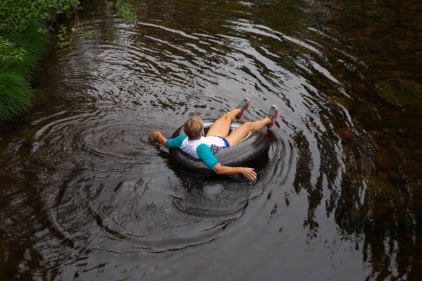 mulher flutuando rio abaixo no tubo interno - inner tube swimming lake water - fotografias e filmes do acervo