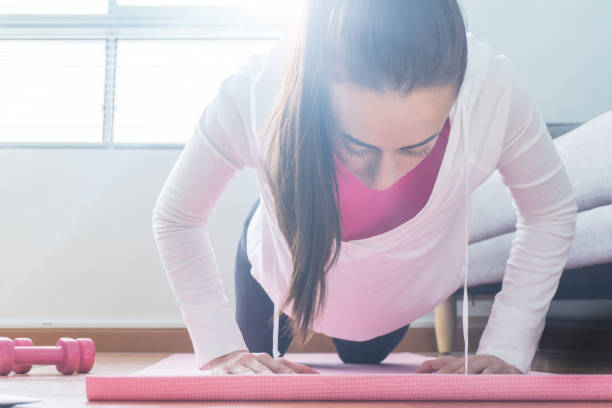 istock Woman exercising at home and doing planks on a mat 1254858740