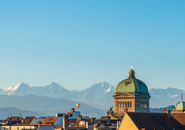 close up view of the dome of the bundeshaus, the swiss government building in bern and the swiss high alps in the background at sunrise - berne swiss culture parliament building switzerland imagens e fotografias de stock