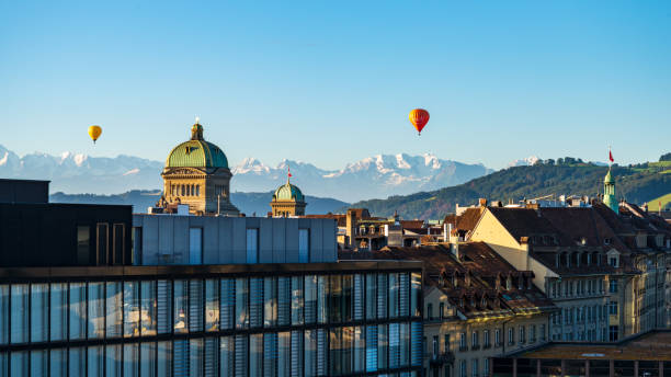 view of the dome of the Bundeshaus, the swiss government building, the Church of the Holy Spirit in Bern and the Swiss high alps in the background at sunrise stock photo