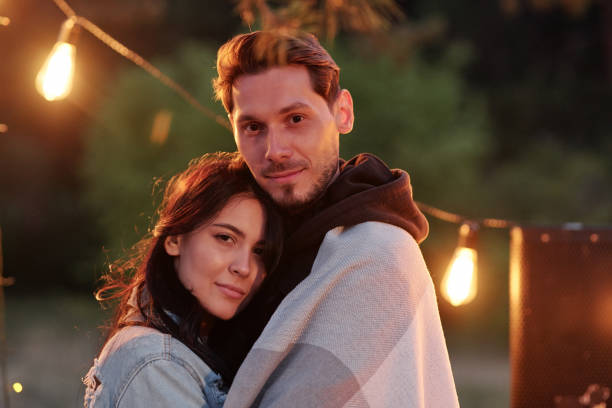 istock Young handsome man wrapped into plaid embracing his pretty girlfriend 1254859339