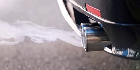 Smoky dual exhaust pipes from a starting diesel car.