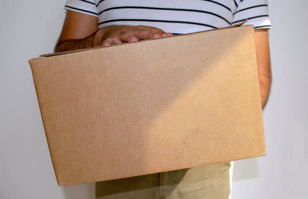 istock Man is holding big cardboard box delivery parcel. 1254860435