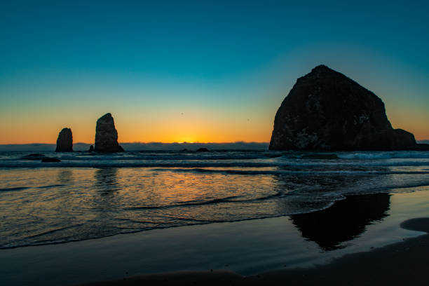 istock Orange sunset glows along horizon with Sea Stacks in silhouette 1254860618