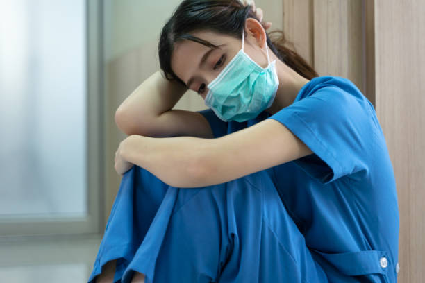портрет усталой истощенной медсестры или врача, сидящего на полу в больнице - doctor tired protective workwear sadness стоковые фото и изображения
