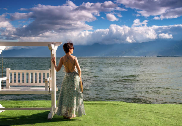 A woman in a dress was standing by the sea looking at the view