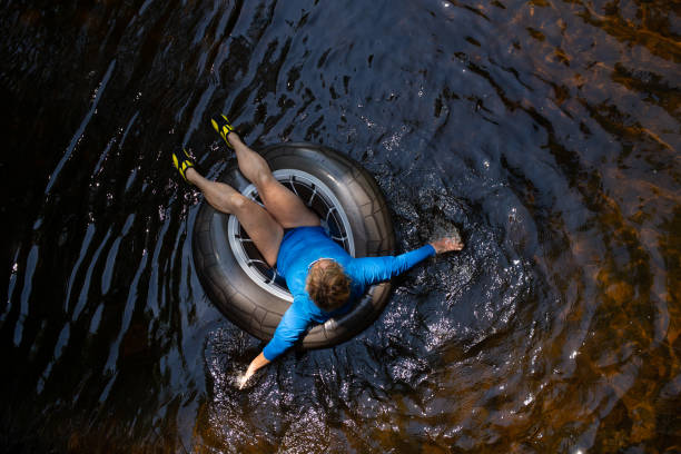 woman floating down a river in inner tube - inflatable ring inflatable float swimming equipment imagens e fotografias de stock