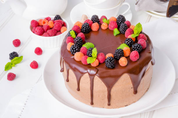 istock Chocolate layer cake with cherry filling and fresh berries on top on a white plate. 1254865114