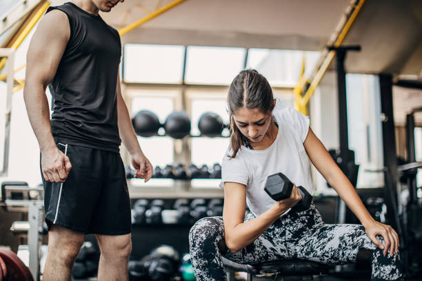 istock Male personal trainer looking a woman training in gym 1254865459