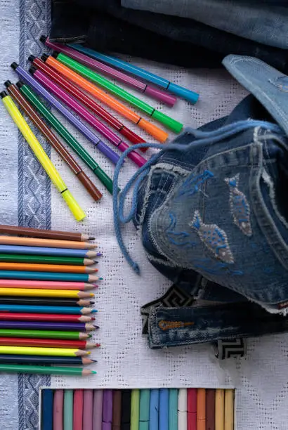 Kids bag from old jeans and colored pencils, crayons and felt-tip pens. Concept of things reuse and back to school handmade.