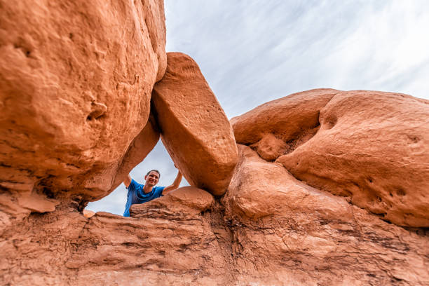 istock Man hiking low angle view behind framing hoodoo sandstone rock formations happy in desert landscape in Goblin Valley State Park in Utah on trail 1254870825