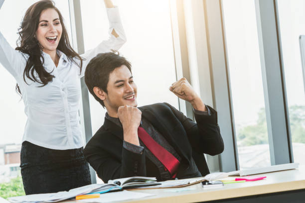 istock Two happy business people celebrate at office 1254870902