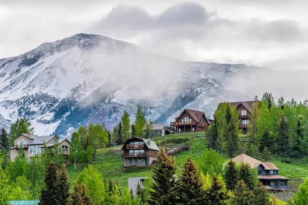 Photo of Crested Butte, USA Colorado town village in summer with clouds and foggy mist morning and houses on hillside with green trees