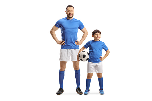Full length portrait of an adult soccer player and a kid holding a ball isolated on white background
