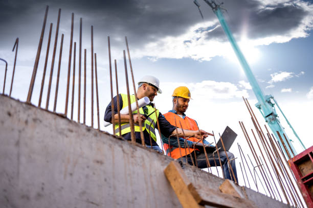 istock Men in hardhat and yellow and orange jacket posing on building site 1254878778