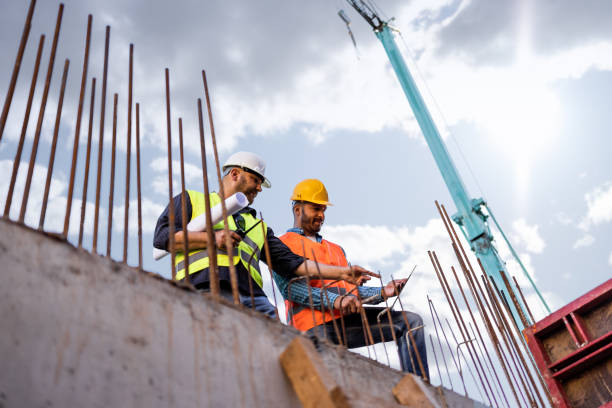 istock Men in hardhat and yellow and orange jacket posing on building site 1254878782
