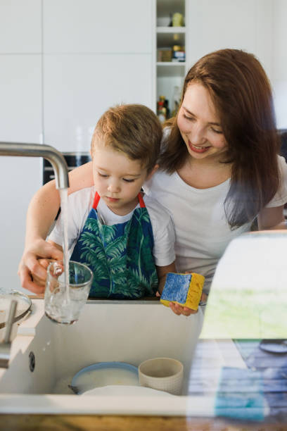 istock Mother and son wash dishes together 1254878848