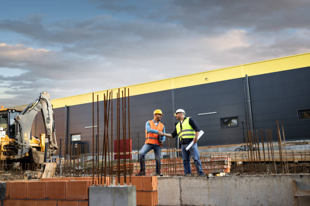 istock Men in hardhat and yellow and orange jacket posing on building site 1254879667