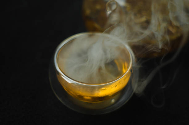 Teapot and glass Cup with hot green tea on a dark background