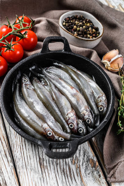 istock Raw smelt with pepper and thyme in a pan. White background. Top view 1254888816