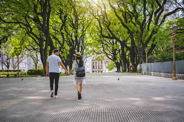 istock Cute couple in love holding hands while walking through the park 1254888829