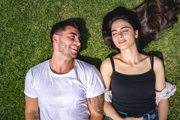 istock Cute serene couple enjoying the sun while lying on the grass at a park 1254890689