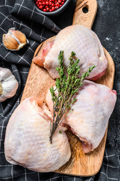 Fresh chicken thigh with skin on cutting board, organic meat. Black background. Top view Fresh chicken thigh with skin on cutting board, organic meat. Black background. Top view. drumstick stock pictures, royalty-free photos & images