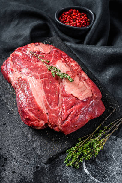 istock Fresh Raw meat Prime Black Angus Chuck roll steak.  Black background. Top view 1254892892