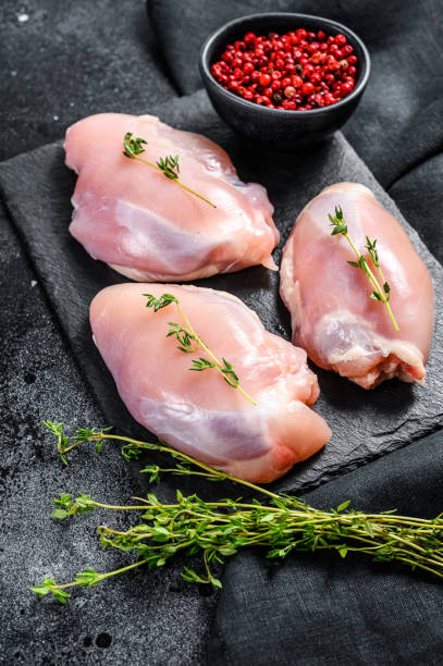 istock Chicken thigh fillet without skin. Black background. Top view 1254893044