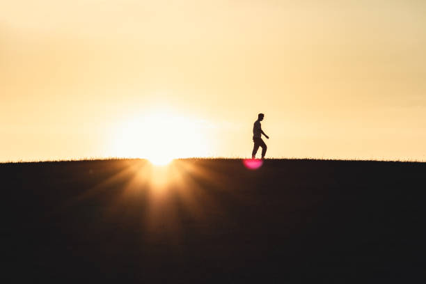 istock Sunset Silhouette Man Walking On Top of Hill 1254893639
