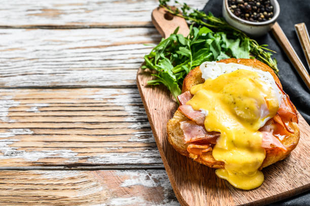istock Brioche sandwich with bacon, egg Benedict and hollandaise sauce. White background. Top view. Copy space 1254893858